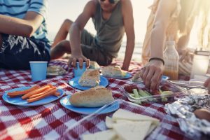 Una familia disfruta de un picnic con diferente tipo de comida en plena playa.