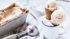 Vanilla icecream with fruit swirl in loaf pan, emaille cup with ice-cream cone and ice scoops, ice cream scoop