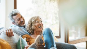 Cheerful mature couple sitting on sofa at home