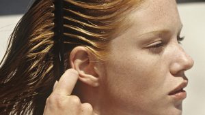 Young woman combing her hair, outdoors