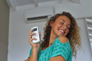 Una chica feliz por tener su casa fresquita con el aire acondicionado.