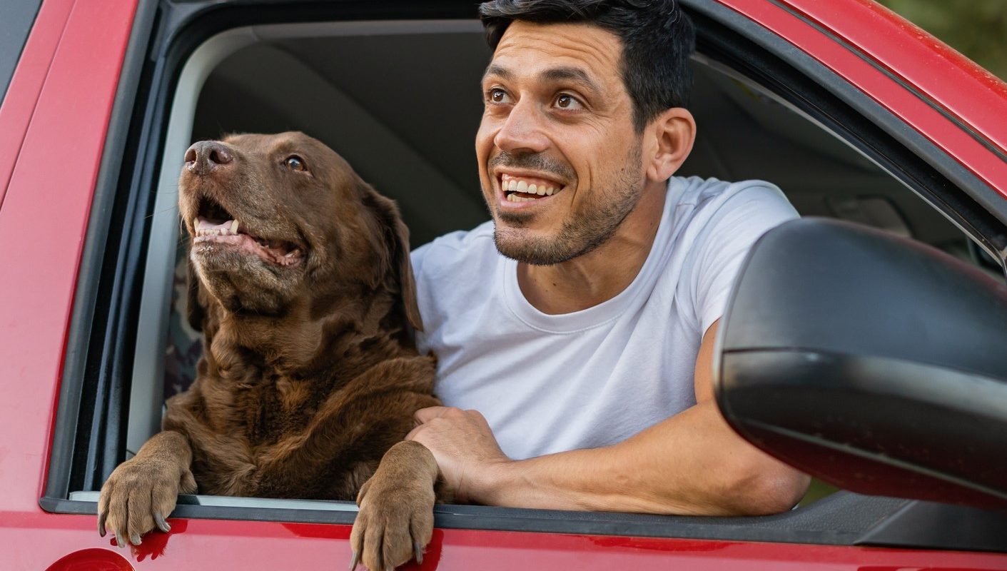 Un dueño junto a su perro disfrutando de su viaje en coche.
