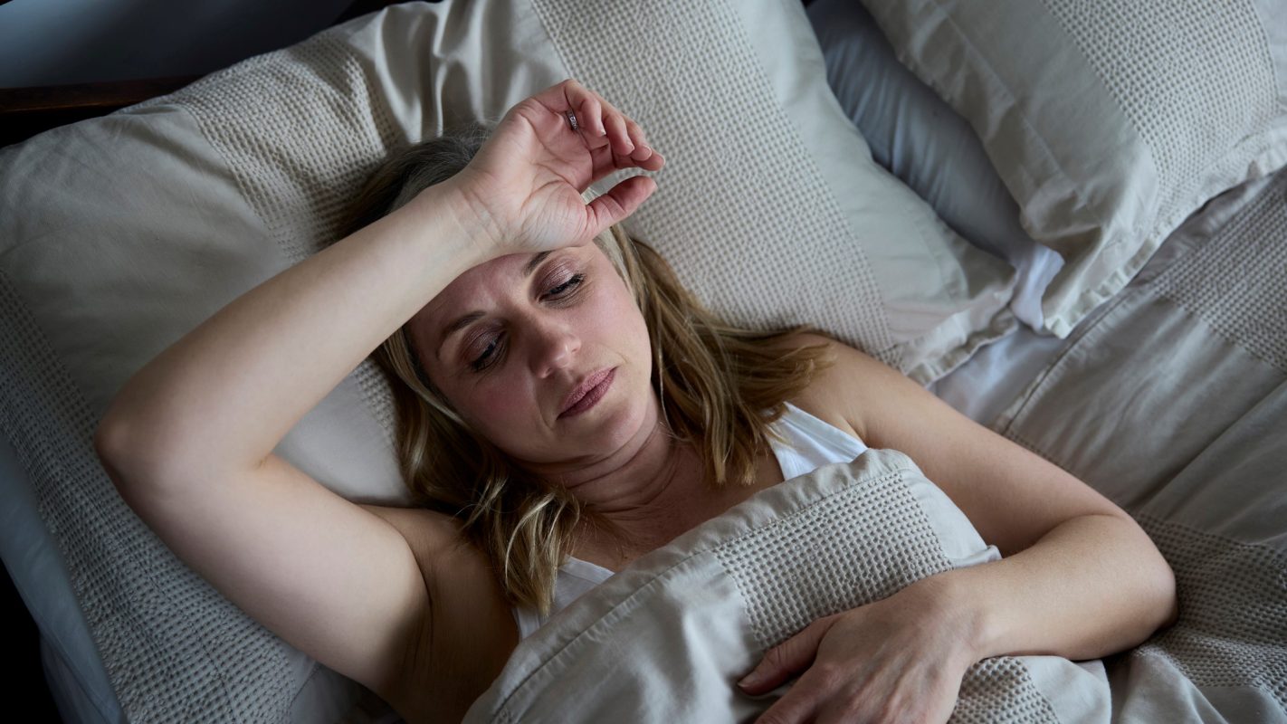 Una mujer tumbada en la cama preocupada tras soñar que se da un beso apasionado con su amigo.