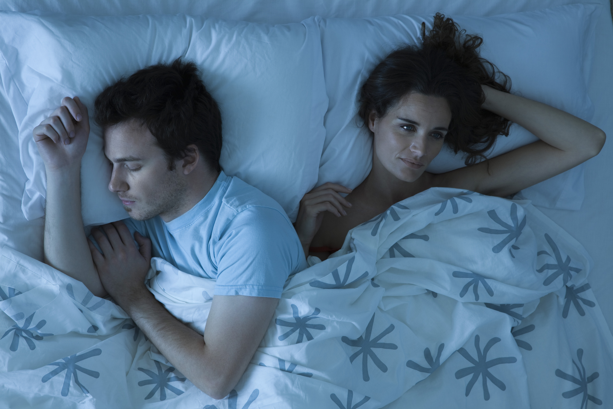 Una pareja tumbada en la cama y uno de los miembros está despierto debido a la pesadilla que ha tenido.