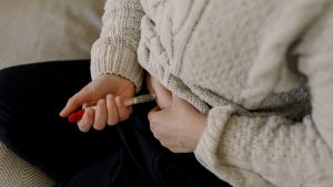 Midsection of lesbian woman injecting syringe in abdomen during IVF test at home