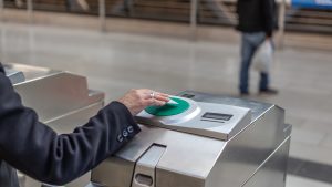 Woman's hand using public transport card to access metro station