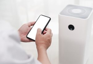 Una persona consultando algo del móvil, mientras se enfría la casa con el aire acondicionado portátil.