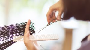 Hairdresser using scissors to cut hair