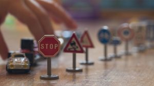 Child playing with toy cars and traffic signals on wooden floor