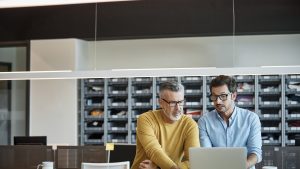 Businessmen using laptop together at desk