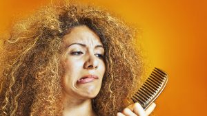 Woman with frizzy and curly hair looking at a comb
