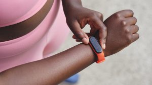 Woman checking time on smart watch while standing on footpath