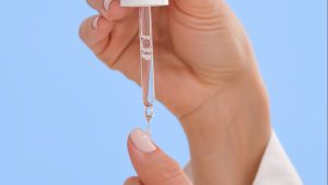 The girl applied a drop of oil to strengthen nails on her finger.