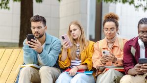 Group of students sitting together and using their smart phones