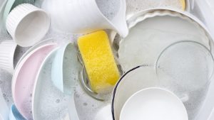 Dishes and bowls in water and bubbles of dishwashing liquid. Kitchen work