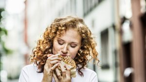 Portrait of young woman eating bagel outdoors