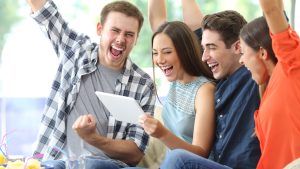 Excited group of friends watching media on tablet at home