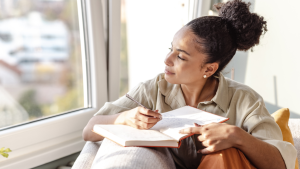Mujer joven escribiendo en una libreta (Getty - Milko)