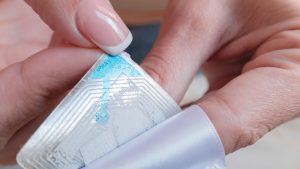 Woman removing an electronic RFID device made for anti-theft purposes from clothing.