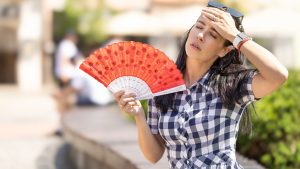 Woman uses hand fan to cool down when summer heat wave hits the city.