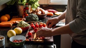 Human hands slicing tomatoes over a wooden table for a vegan meal