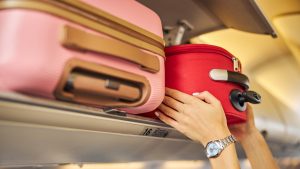 Hands laying down a carry-on baggage on an upper shelf