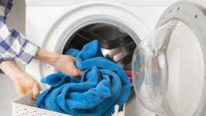 persons hand put dirty clothes in the washing machine b