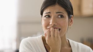 Afraid mixed race woman biting fingers