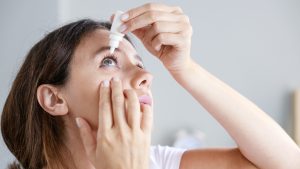 Young woman putting eye drops