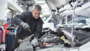 Engineer checking oil level in car service centre