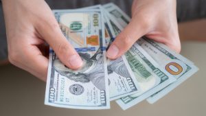 Close up of someone hands holding and counting American dollar banknotes in her hand.
