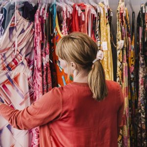 Woman looking at dress hanging on rack while standing at store