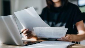 Cropped shot of young Asian woman handling personal banking and finance with laptop at home. Planning budget and calculating expenses. Managing taxes and financial bills. Wealth management. Digital banking habits. Smart banking with technology