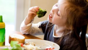 A young girl eating healthy vegetables