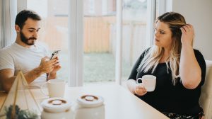 A woman looks insecure as her partner ignores her to look at his phone