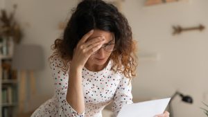 Confused young female open official letter about loan rejection