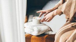 Woman taking care of her skin. Young woman in bathroom applying cream.