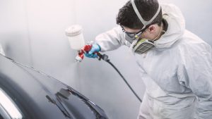Auto painter painting a car inside a paint booth