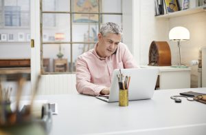 Mature creative man working on laptop & on phone