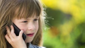 Cute child young girl talking on cellphone outdoors. Children and modern technology, communication concept.