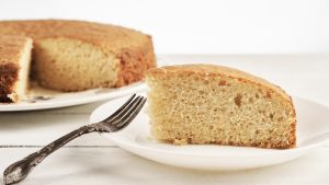 Close up of a slice of homemade sponge cake on a white wooden table
