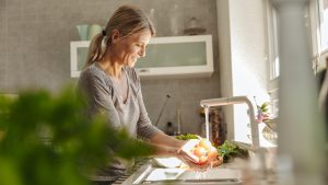 Woman in kitchen washing tomatoes
