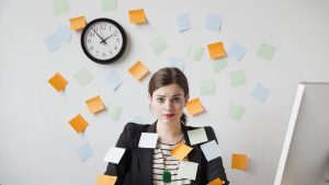 Studio shot of young woman working in office covered with adhesive notes