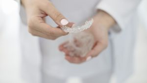hands of dentist holding dental aligner