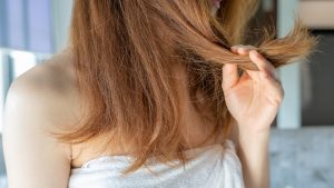 Cropped shot view of woman holding her damaged split ended and messy hair.