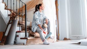 a young woman joyfully sits against the background of repairs in the house