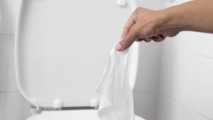 man throwing a wet wipe to the toilet