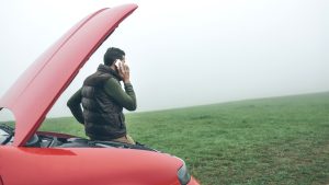 Man talking on cell phone next to broken car