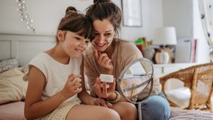Mother and daughter having a spa day, taking care of their skin, applying facial cream.