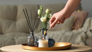 Woman lighting candle at wooden table in living room, closeup